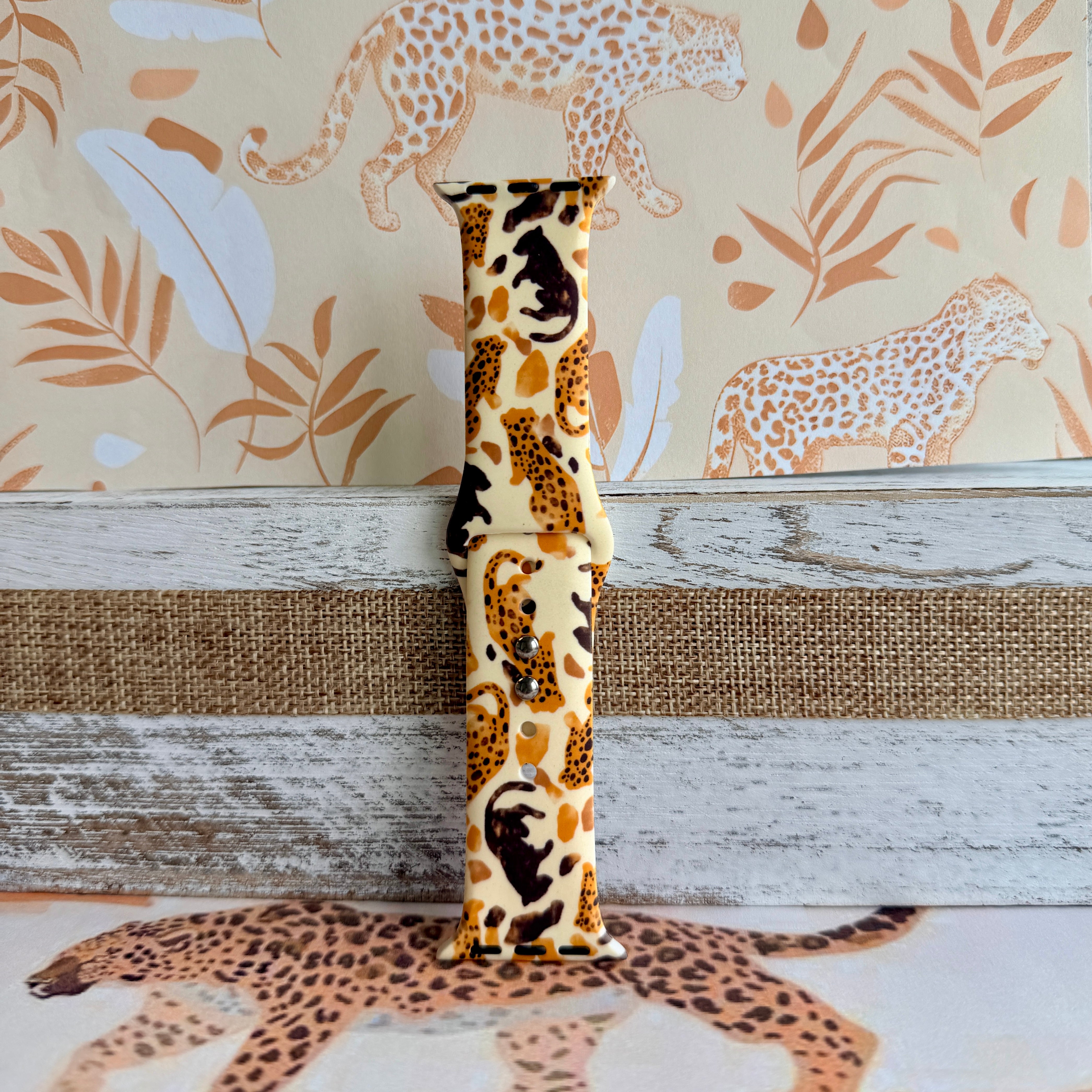 Golden Wildcat Apple Watch band with spotted leopards in golden and brown tones on cream background with safari wallpaper
