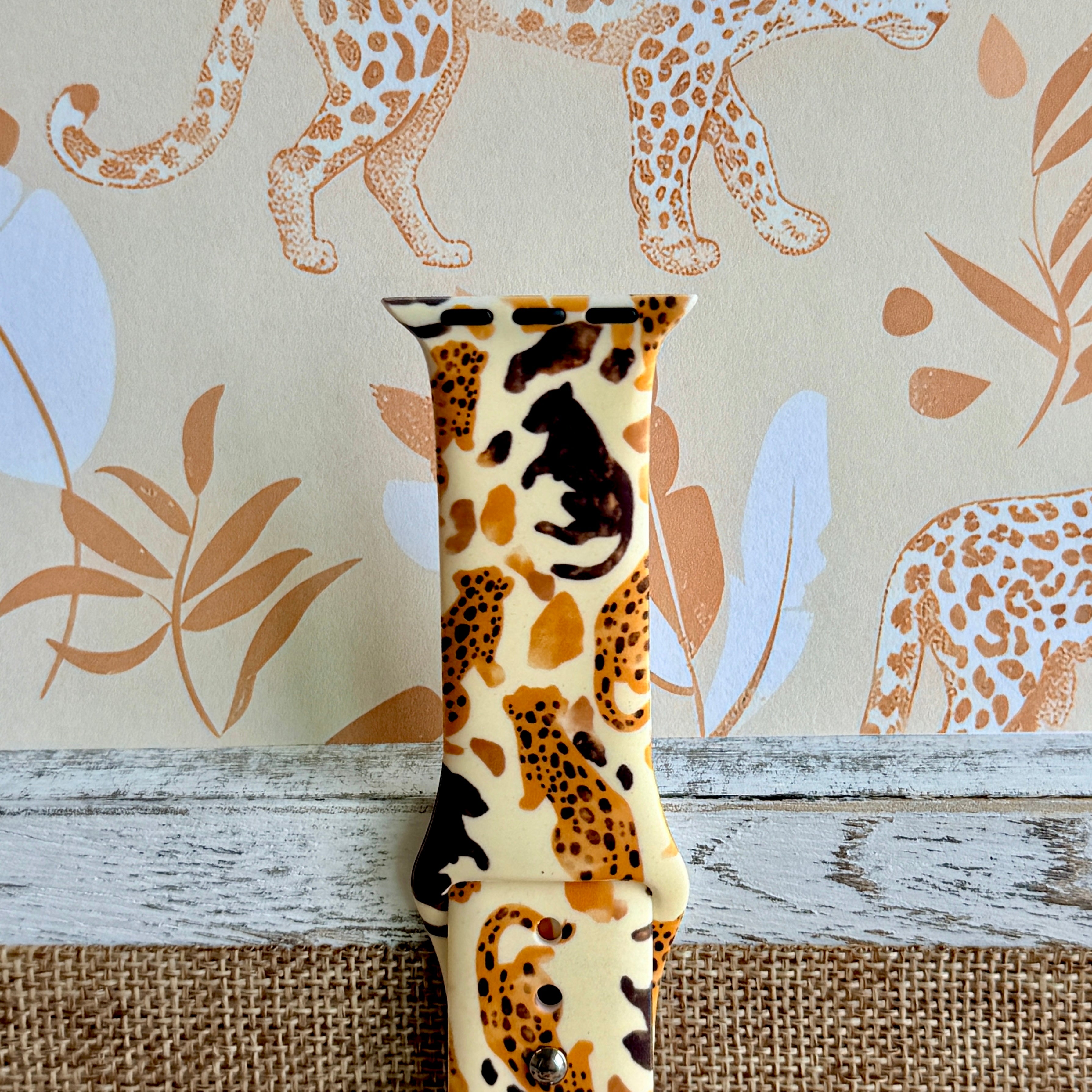 Golden Wildcat Apple Watch band with spotted leopards in golden and brown tones on cream background with safari wallpaper
