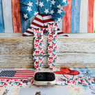 American Girly silicone Apple Watch band with red and blue coquette bows, mini cowboy boots, stars, and "American Girly" script on a white base, shown displayed and worn on Apple Watch against a patriotic 4th of July backdrop.