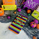 Main Witch Energy Wavy Luxe MagSafe iPhone case with the matching MagSafe grip ring attached, on a Halloween set with glitter pumpkins.