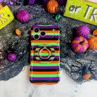 Main Witch Energy MagSafe grip ring attached to the matching striped Wavy Luxe case, on black spiderweb mesh with glitter pumpkins.