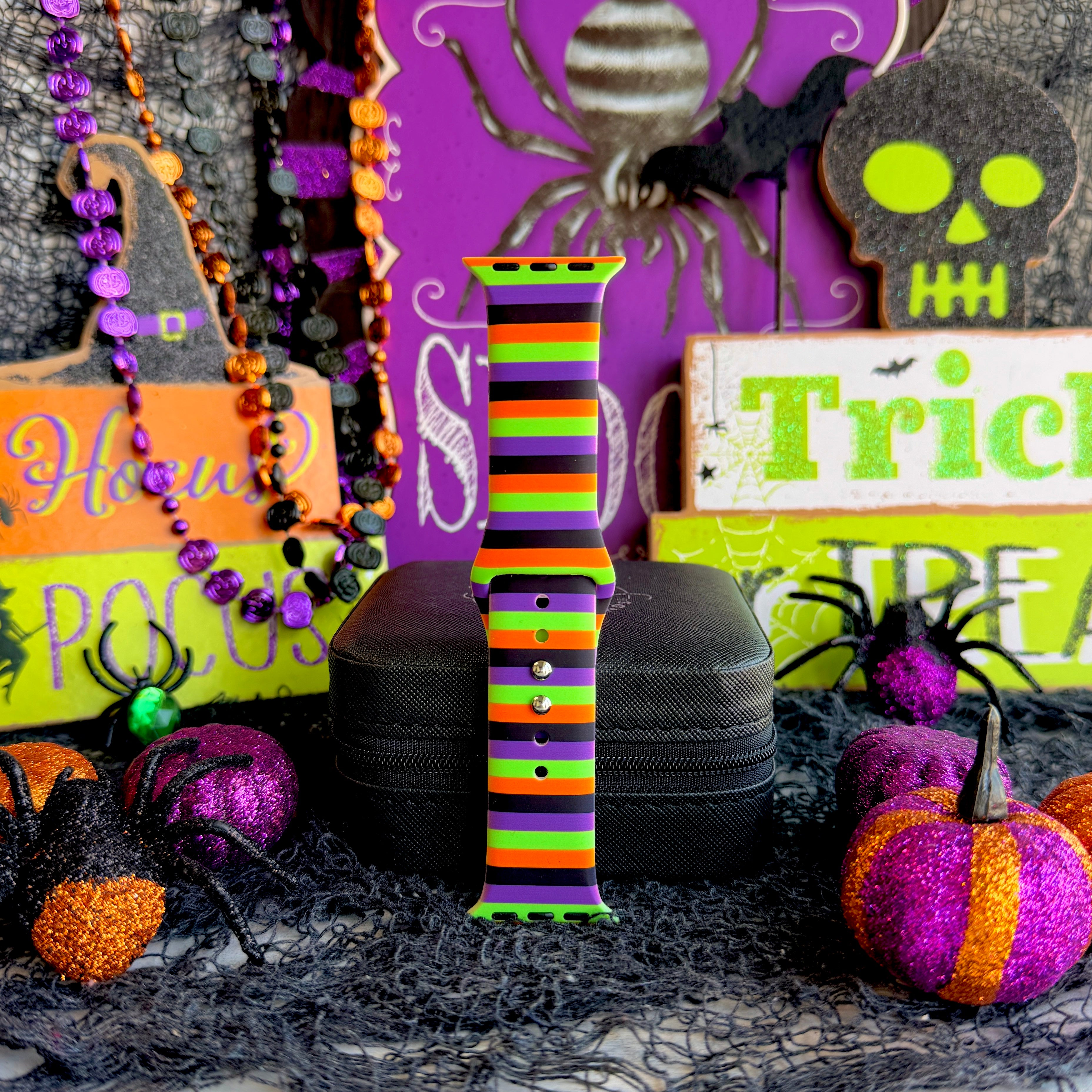 Single Main Witch Energy Apple Watch band strap standing tall beside a purple and orange beaded garland and Trick or Treat sign.