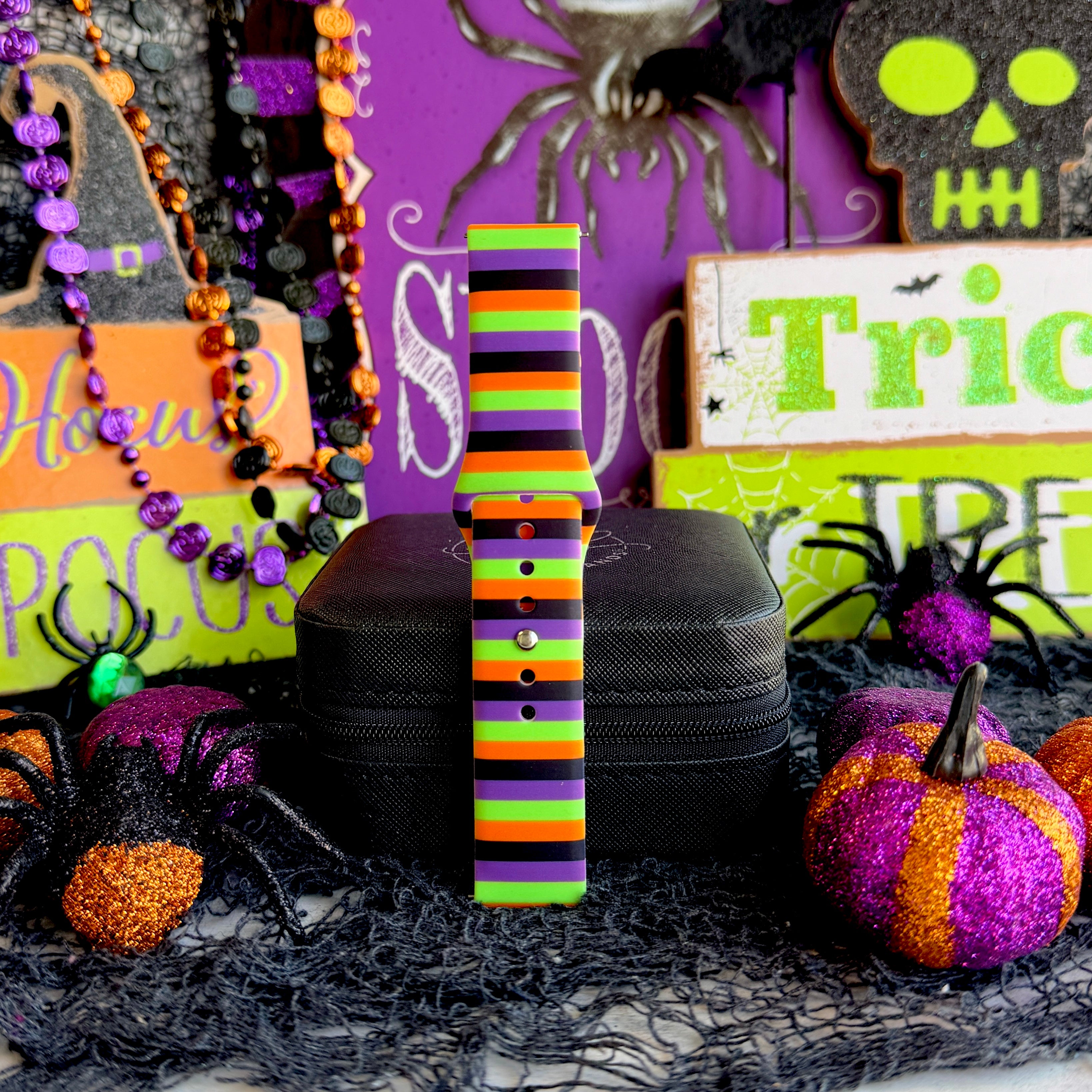 Single Main Witch Energy Samsung Galaxy Watch band strap standing tall beside a green skull sign and glitter pumpkins.