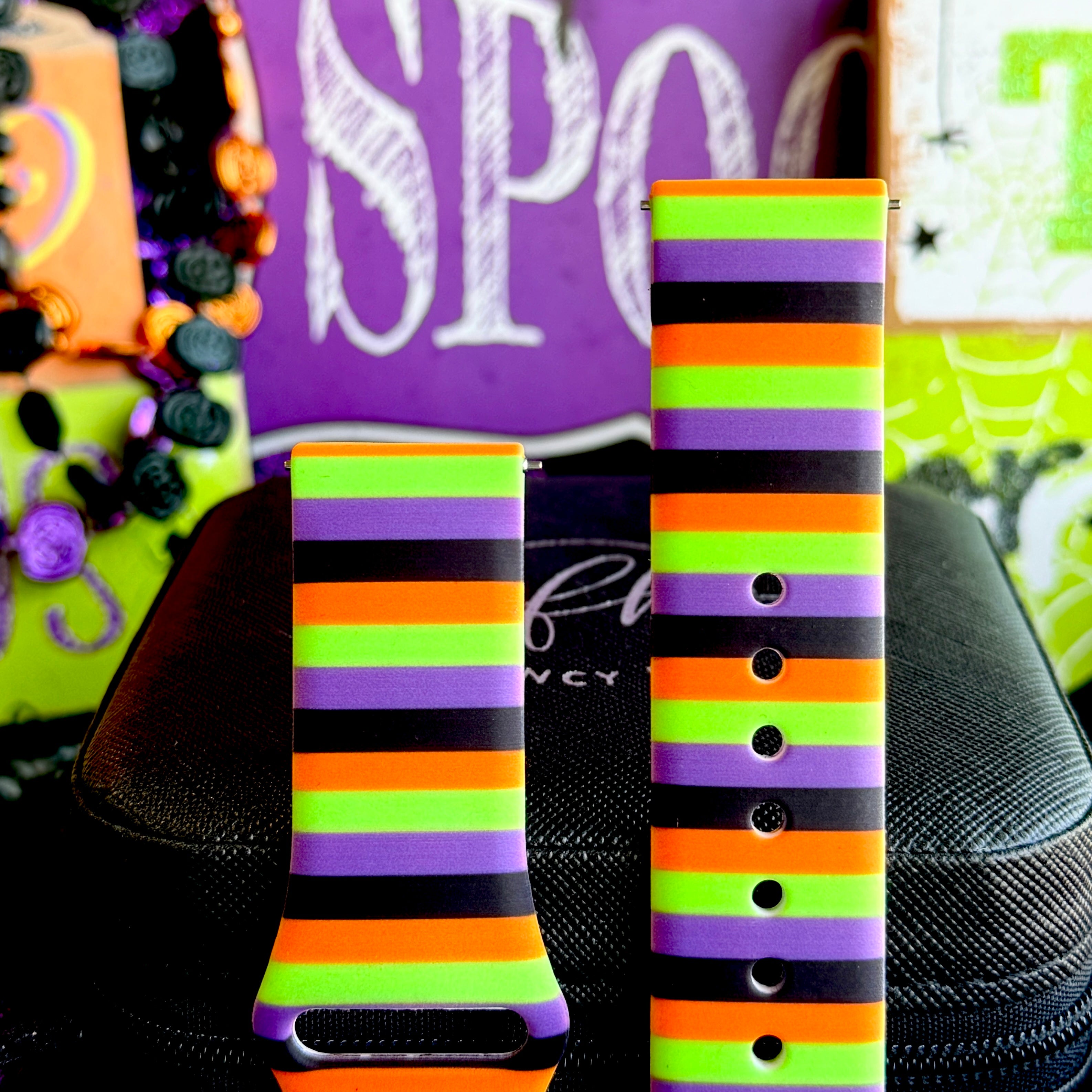 Both halves of the Main Witch Energy Samsung Galaxy Watch band standing upright against a purple SPOOKY sign.