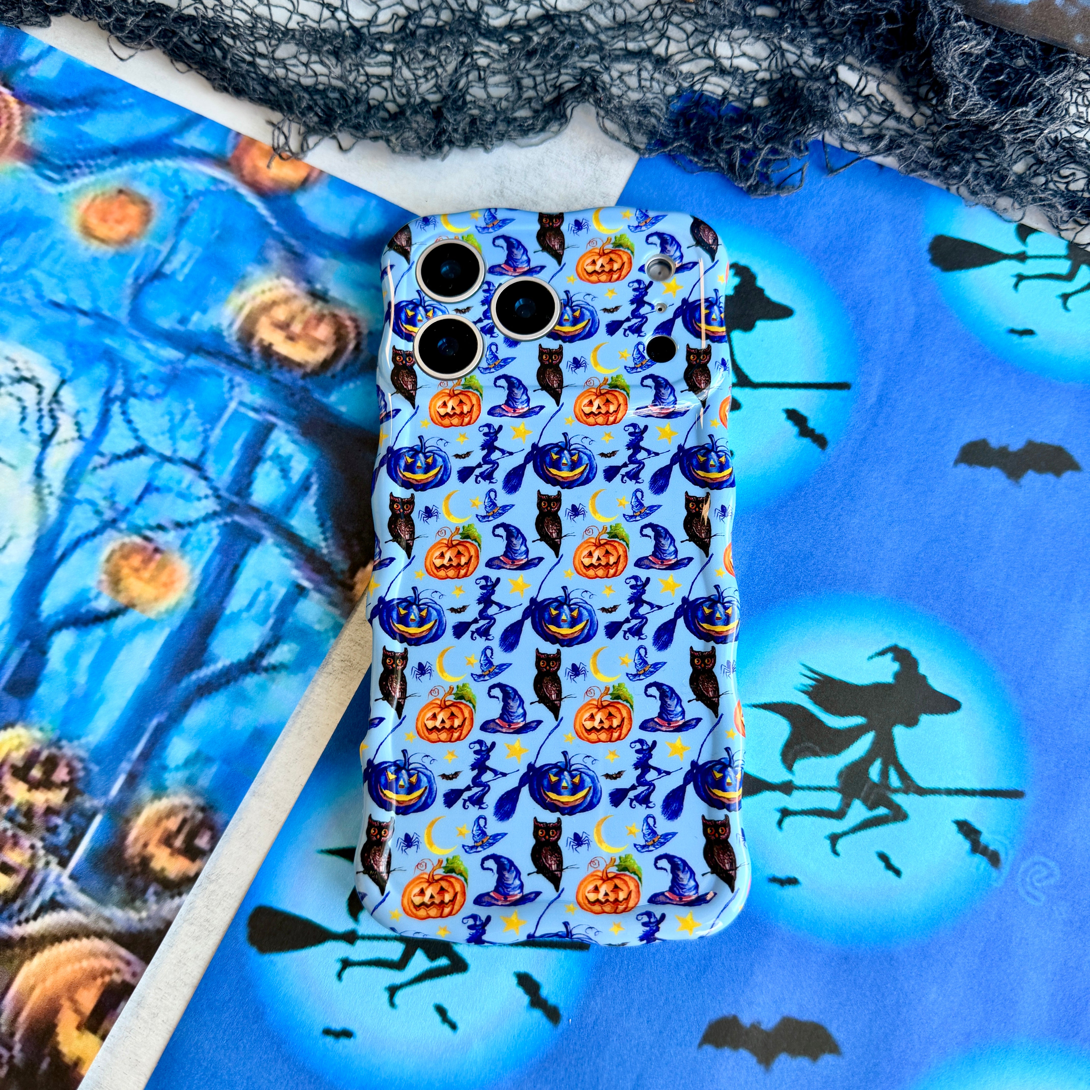 The Bewitching Hour Wavy Luxe MagSafe iPhone case in periwinkle blue with watercolour witch hats, black owls, jack-o'-lanterns and crescent moons