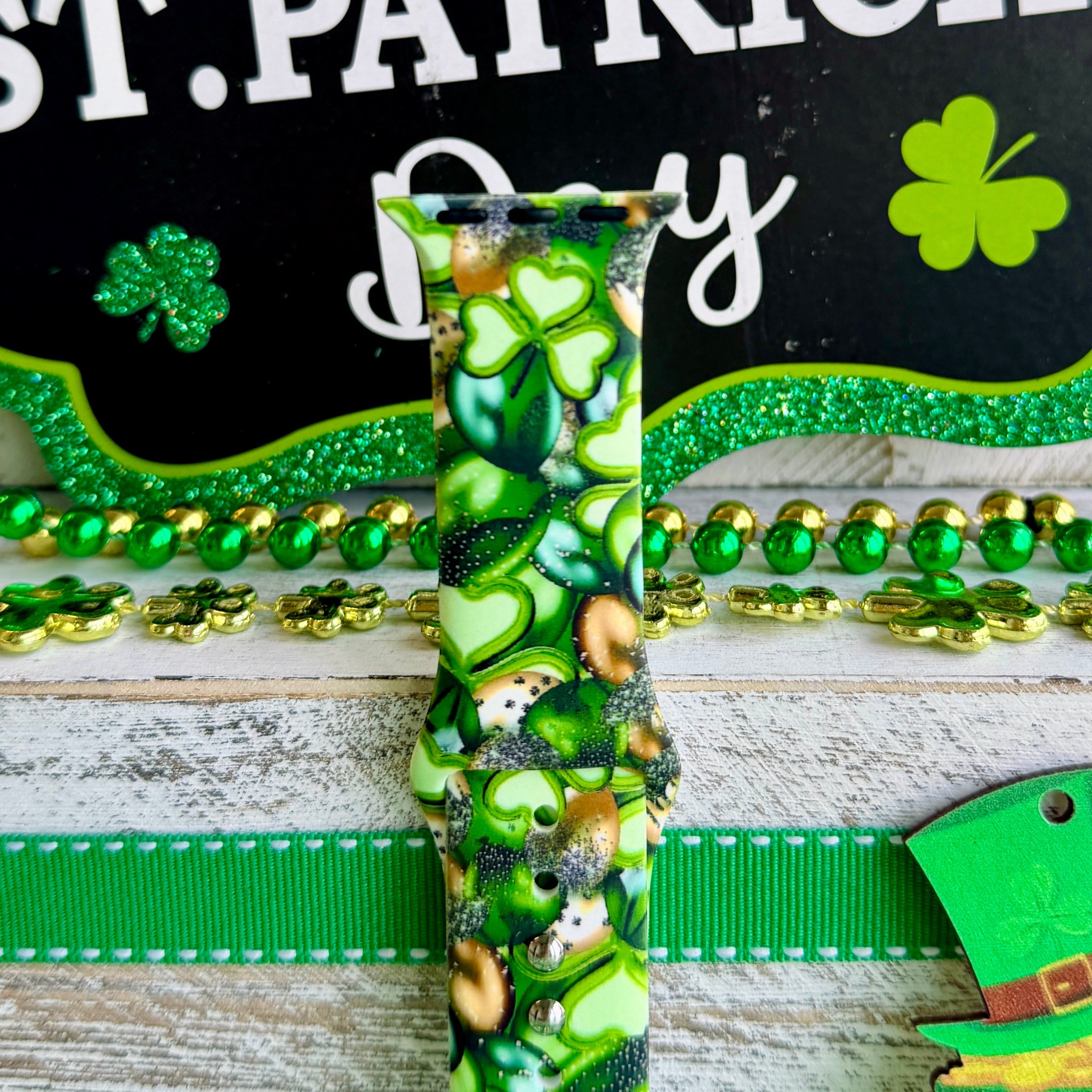 St. Patrick's Day Apple Watch band with green shamrocks, gold coins, and leprechaun hats on festive display
