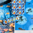 The Bewitching Hour Scrunchie Phone Wrist Strap clipped to the matching light blue witch hat and jack-o-lantern phone case, hanging from the metal clasp.