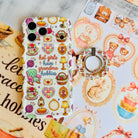 It's Giving Grandma Hobbies cozy grandmacore MagSafe phone grip ring with knitting yarn, rocking chairs, teacups, and pies on a white background compatible with iPhone and Samsung