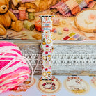 It's Giving Grandma Hobbies silicone Apple Watch band with "hot girls have grandma hobbies" script, patchwork hearts, yarn balls, knitting needles, embroidery hoops, lanterns, pies, and teacups on a cream base, shown displayed and worn on Apple Watch against a cottagecore craft backdrop.
