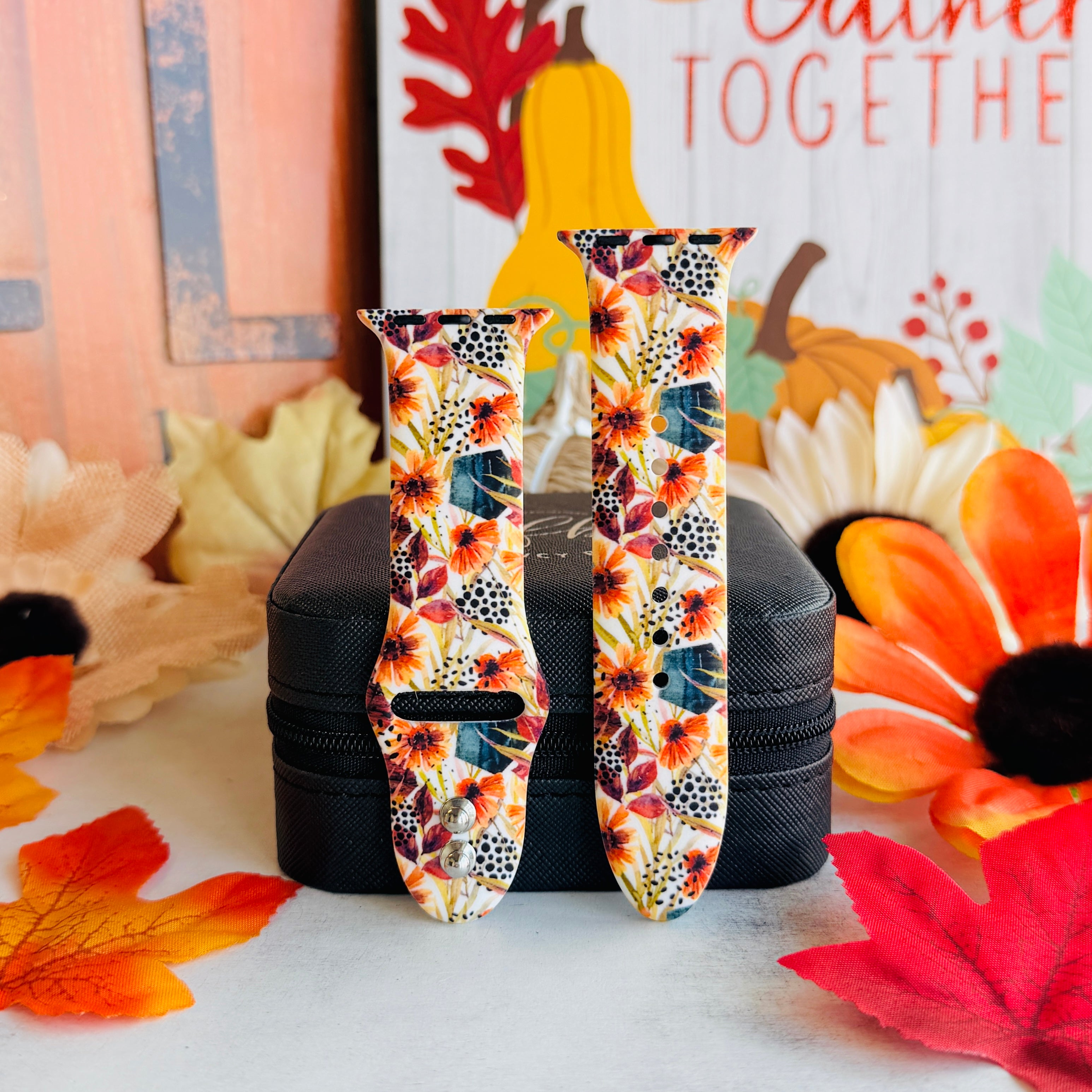 Sienna Petals Apple Watch band shown in both size options on a black stand, cream rust floral print with black dot accents.