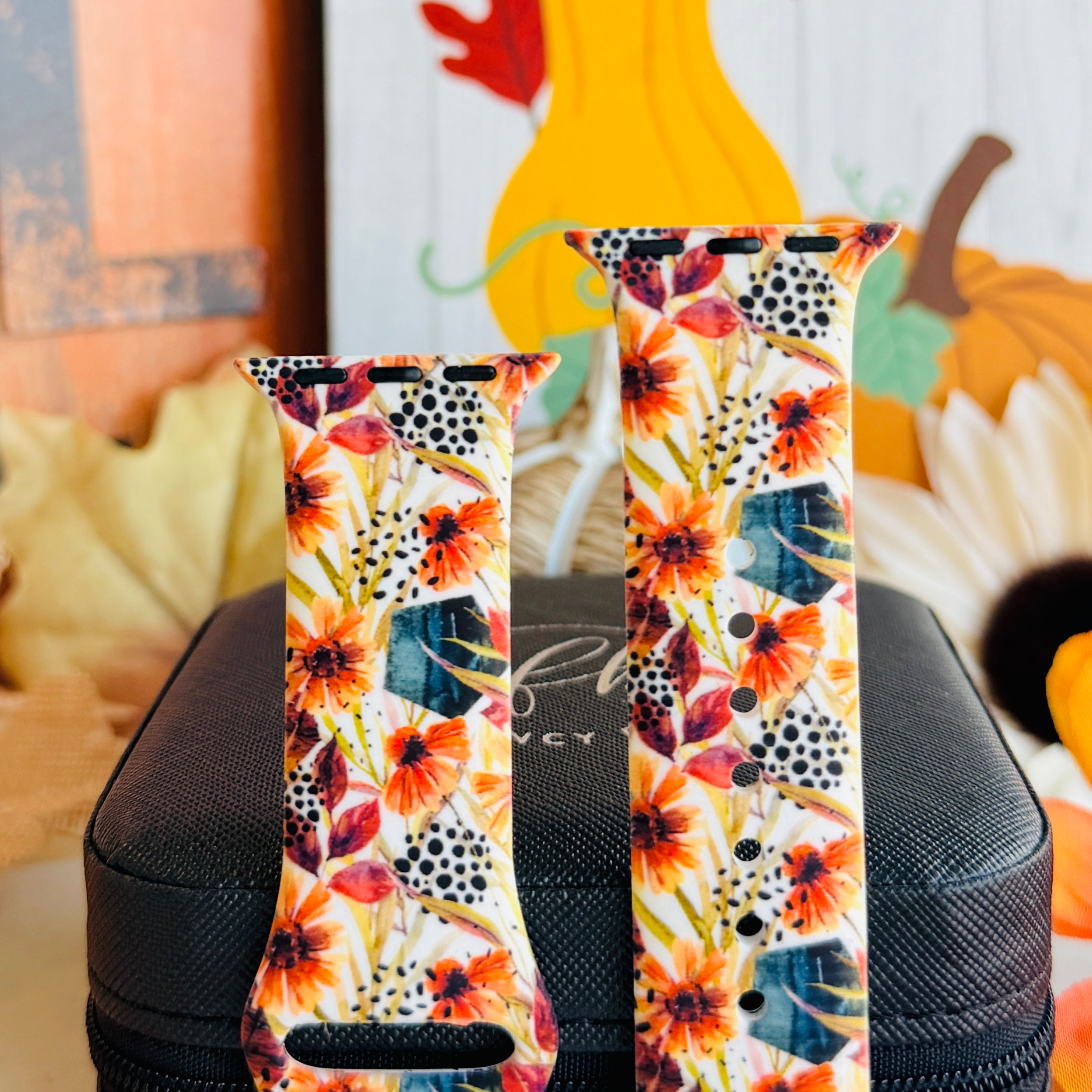 Both sizes of the Sienna Petals Apple Watch band standing side by side, close view of the rust flowers, deep teal foliage and black dot clusters.