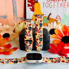 Sienna Petals silicone Apple Watch band shown in both sizes with an Apple Watch at the base, cream with burnt orange watercolor daisies and teal leaves.