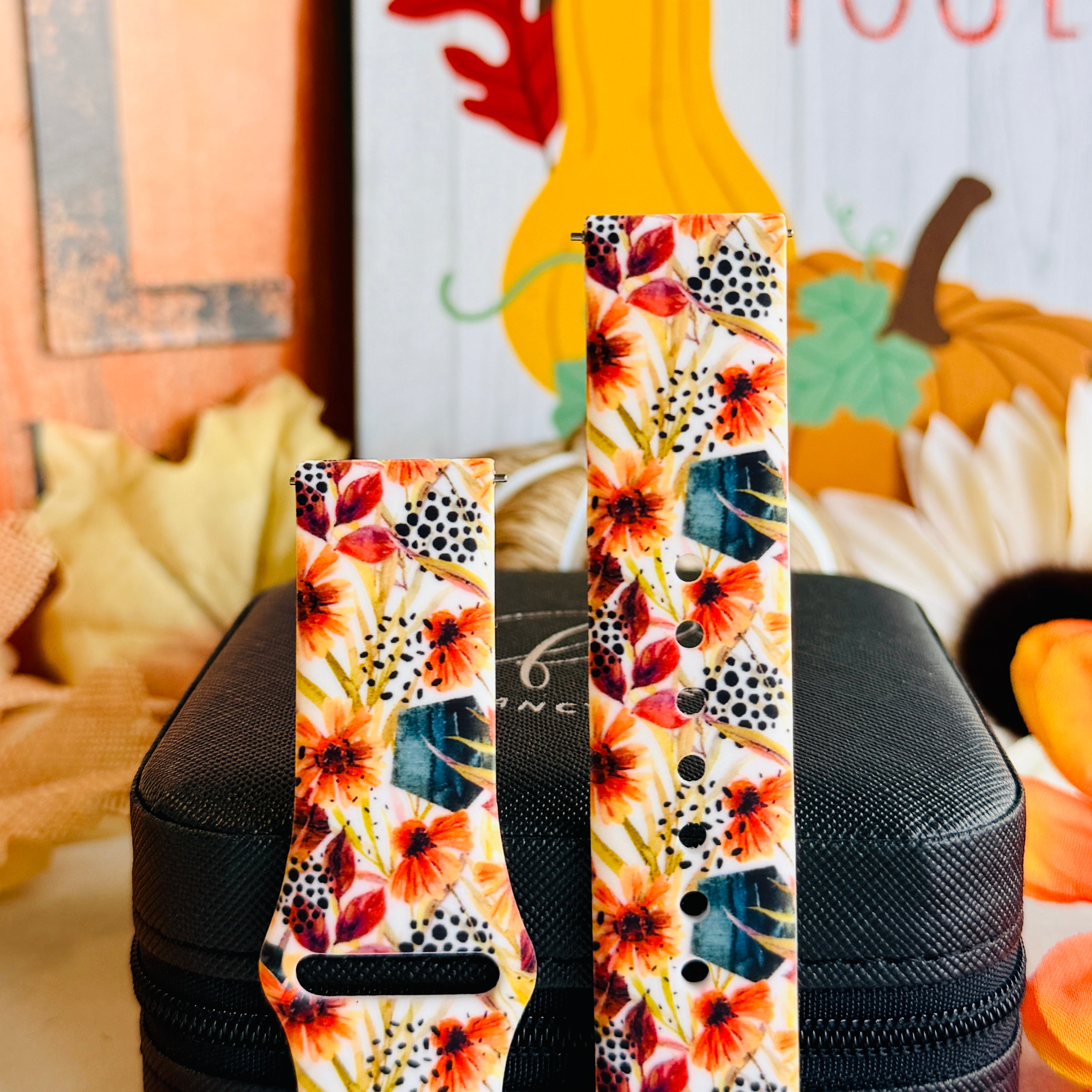 Both sizes of the Sienna Petals Samsung Galaxy Watch band side by side, close view of the burnt orange daisies, teal leaves and black dots.