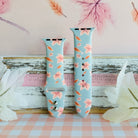 Autumn Breeze Apple Watch band in both size options on a weathered wood ledge with pale silk leaves and a pink gingham cloth.