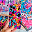 Trendy wavy iPhone case featuring a vibrant street-art collage of electric blue and yellow butterflies over neon pink paint splatters with a high-gloss finish.