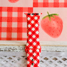 Close view of the Red Barn Babe Apple Watch band showing the crisp red and white gingham weave and the stainless steel closure studs.
