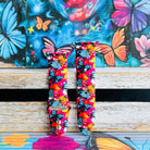 Rebel Wings silicone Apple Watch band with graffiti-style butterflies in blue, orange, yellow, and white over a hot pink and magenta paint-splatter background, shown displayed and worn on Apple Watch against a colorful street art butterfly backdrop.
