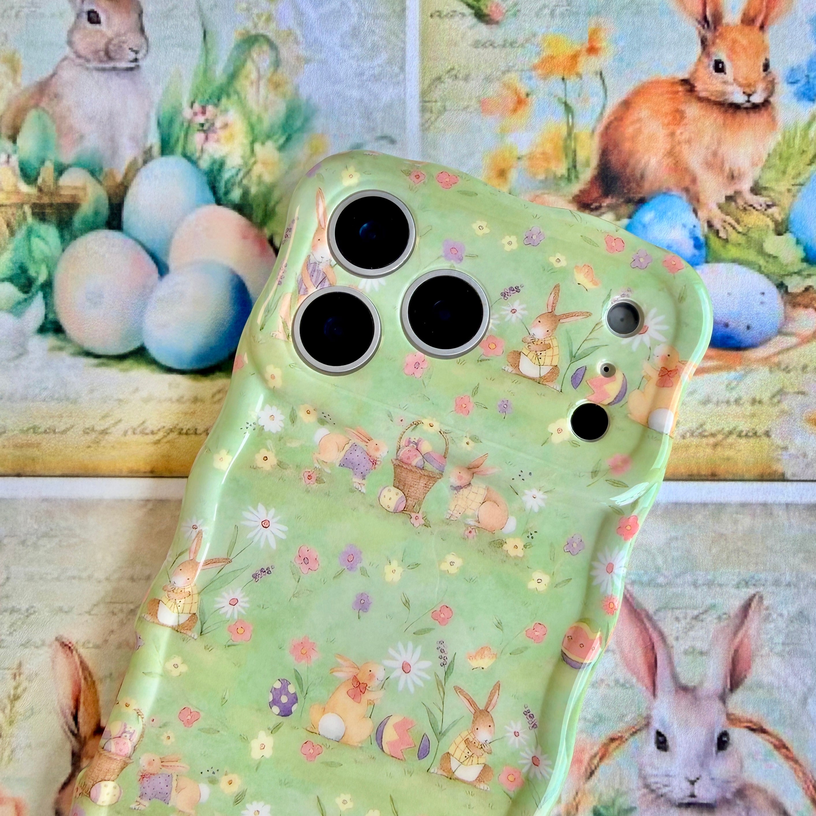 Sage green wavy iPhone case featuring a vintage watercolor pattern of bunnies, Easter eggs, and spring flowers.