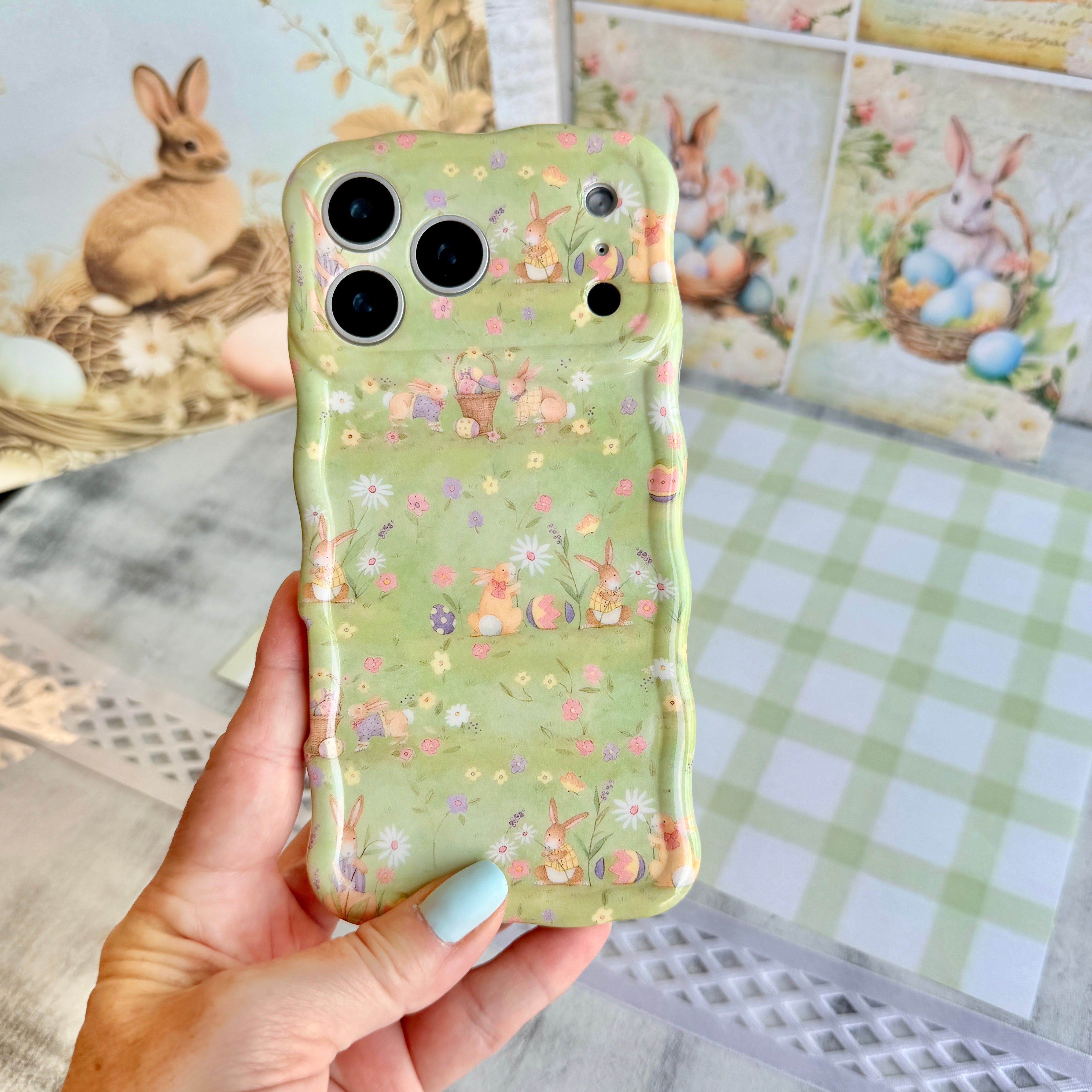 Sage green wavy iPhone case featuring a vintage watercolor pattern of bunnies, Easter eggs, and spring flowers.