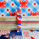 Sweet Freedom 250 silicone Samsung Galaxy Watch band celebrating America's 250th anniversary with "250 Years 1776" emblem, American flag, fireworks, red bow, and red, white, and blue tie-dye swirl with star sparkle, shown displayed and worn against a patriotic 4th of July backdrop.