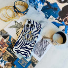 Zebra, Obviously navy zebra print iPhone case wearing the matching navy and white zebra MagSafe grip ring, styled on a designer fashion collage with gold hoops and a studded cuff.