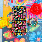 Bloom Bonita folk art floral MagSafe phone grip ring with vibrant pink red yellow and teal flowers on a black background compatible with iPhone and Samsung