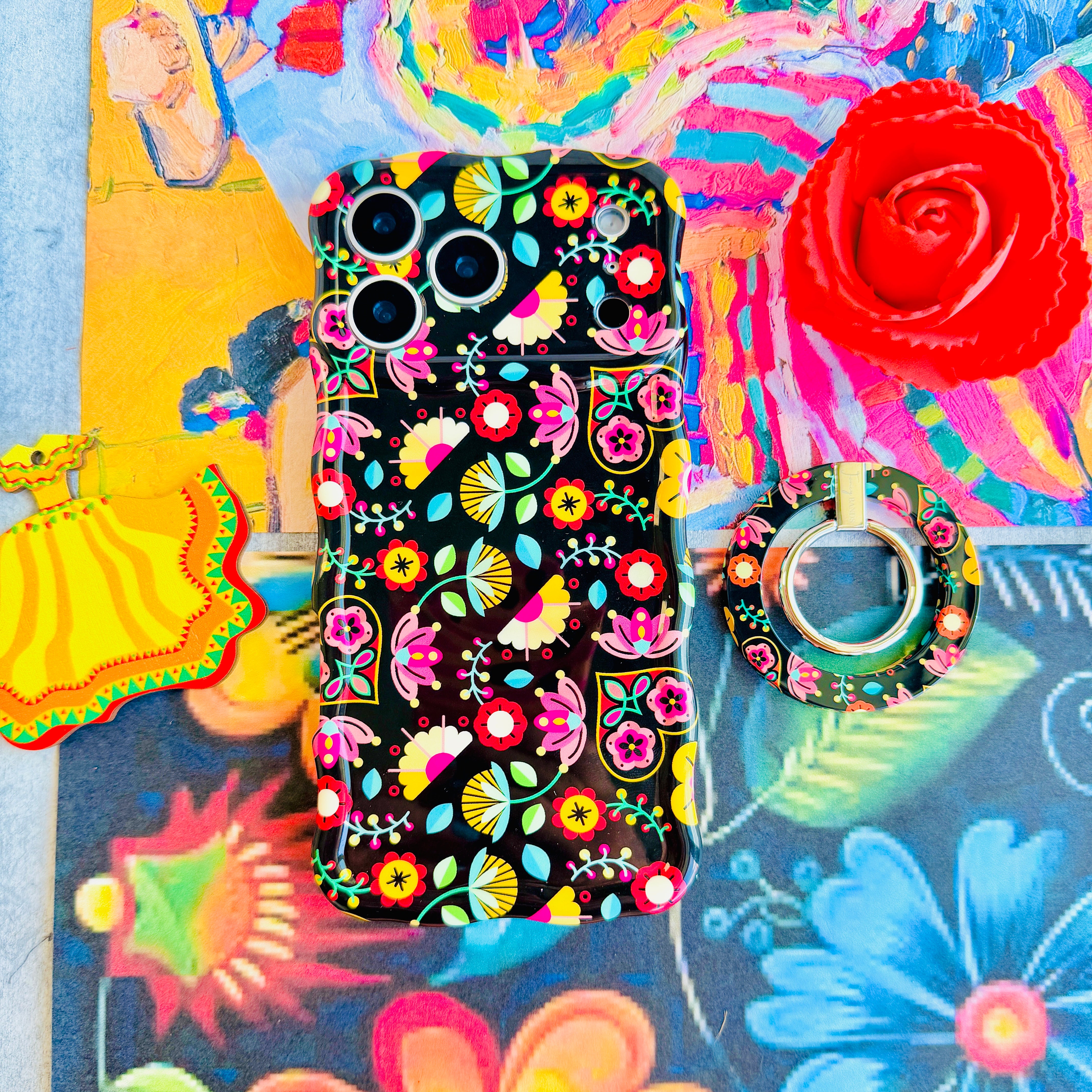 Bloom Bonita folk art floral MagSafe phone grip ring with vibrant pink red yellow and teal flowers on a black background compatible with iPhone and Samsung