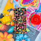 Bloom Bonita folk art floral MagSafe phone grip ring with vibrant pink red yellow and teal flowers on a black background compatible with iPhone and Samsung