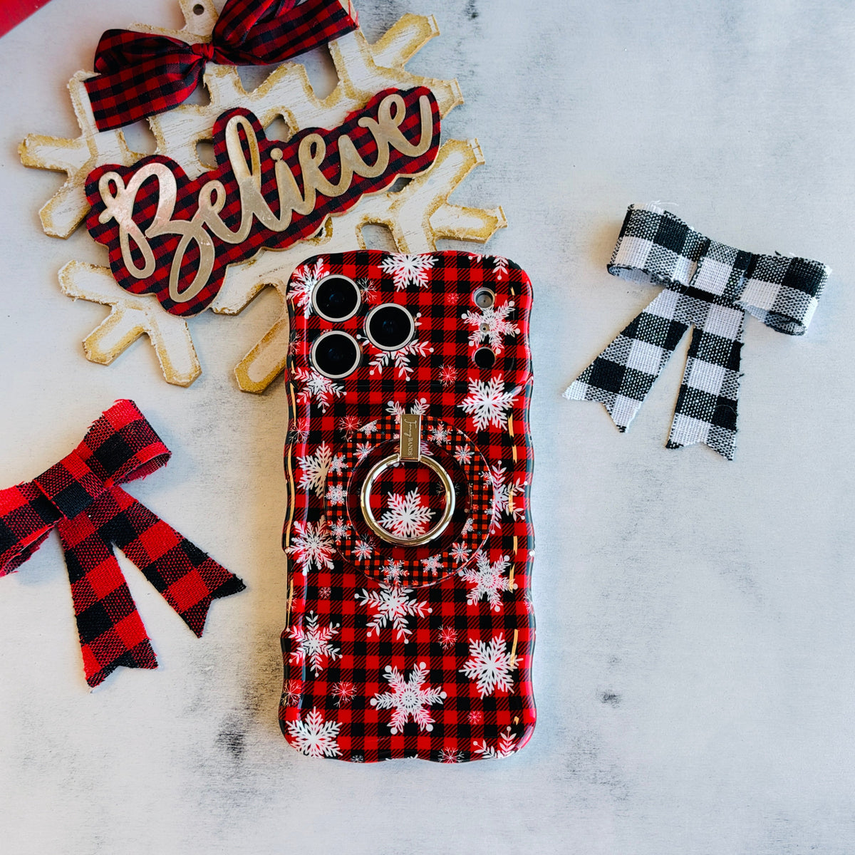 Buffalo Plaid Snowflake Hold It Fancy MagSafe grip ring attached to the matching buffalo check iPhone case, with a Believe sign and check bows