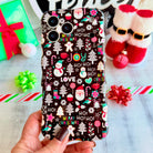 Hand holding the Jolly Wrist-mas Wavy Luxe MagSafe iPhone case, Santas, snowmen and HO HO HO lettering on black