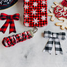 Buffalo Plaid Snowflake scrunchie phone wrist strap clipped to the matching iPhone case, with a Believe sign and buffalo check bows