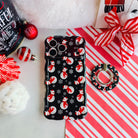 Snowman MagSafe grip ring beside the matching iPhone case, on candy cane stripes with a Santa hat and ornaments