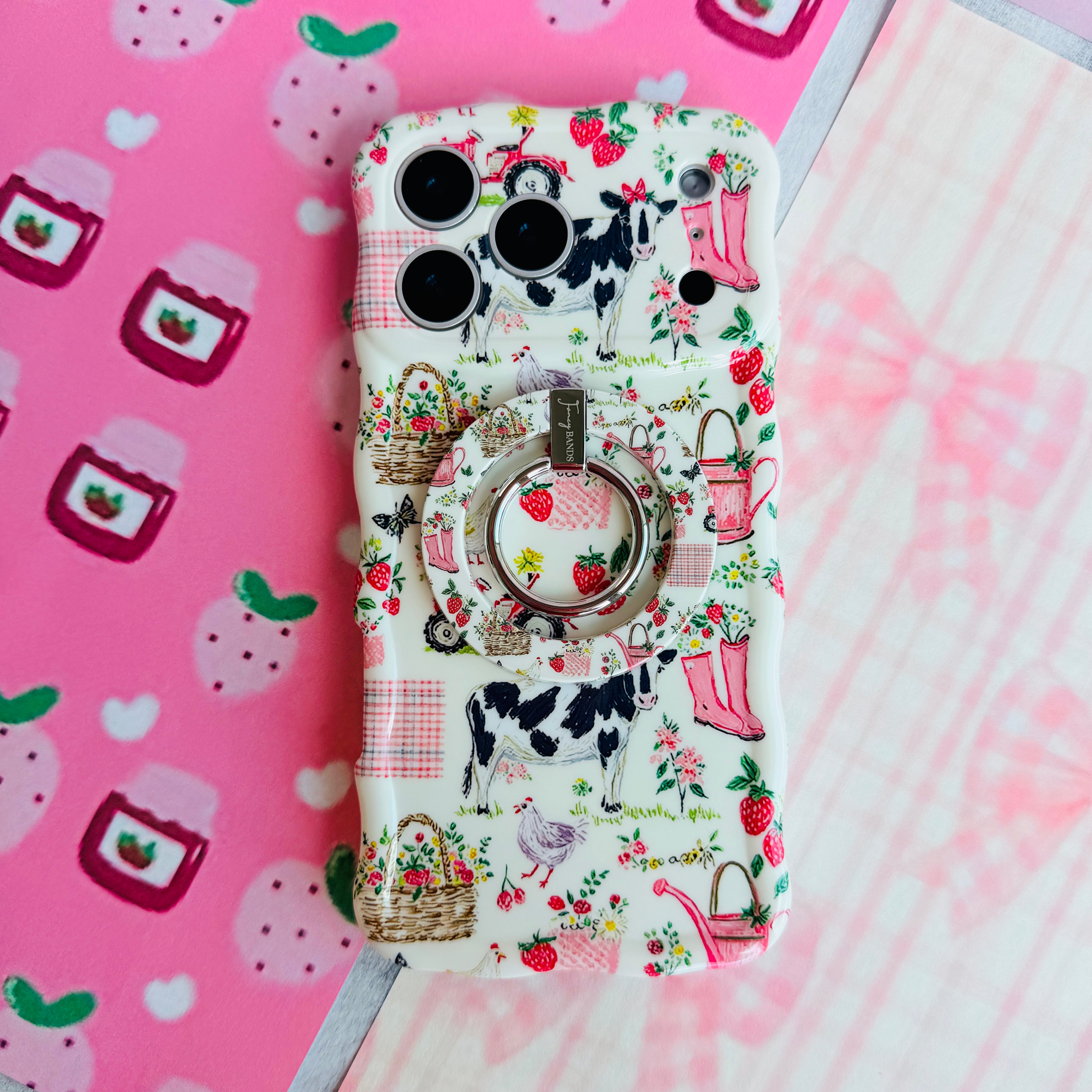 Farm Girl Cutie cottagecore MagSafe phone grip ring with pink watering cans, strawberries, rain boots, and gingham patterns on an off-white background compatible with iPhone and Samsung