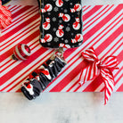 Snowman scrunchie phone wrist strap clipped to the matching snowman Wavy Luxe iPhone case, on candy cane stripes with a Santa hat and ornaments