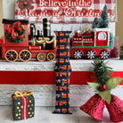 Decorative Christmas scene with a train, gift box, and bell on a wooden surface.