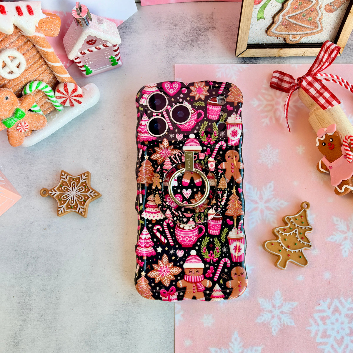 Merry Mugs & Ginger Hugs MagSafe grip ring attached to the matching iPhone case, with gingerbread cookies and a gingerbread house