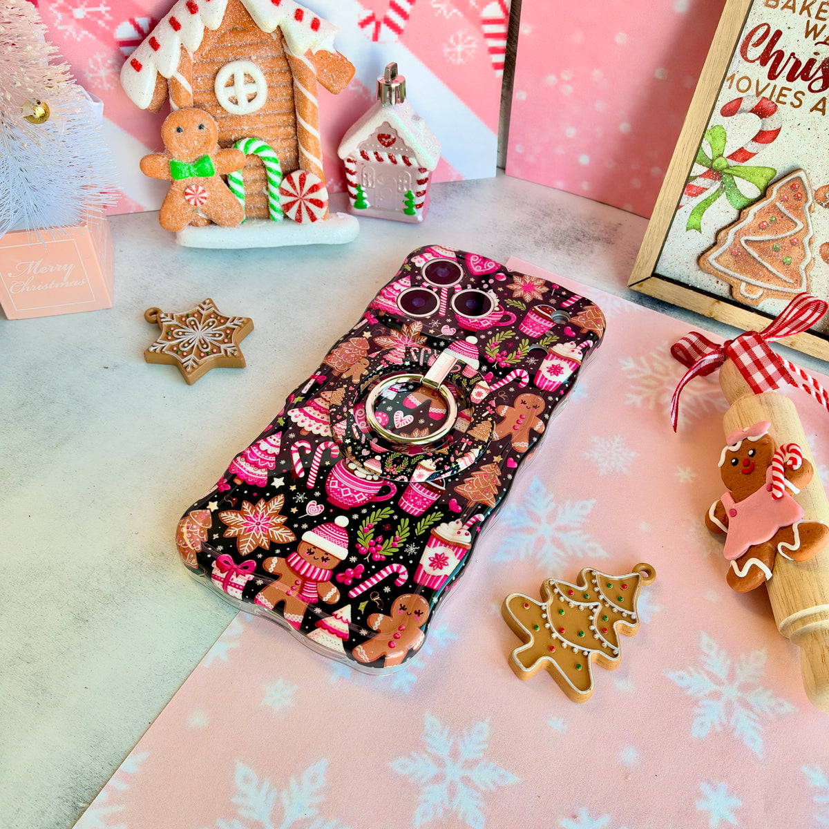 Merry Mugs & Ginger Hugs iPhone case with the matching MagSafe grip ring attached, with gingerbread cookies and a gingerbread house
