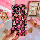 Hand holding the Merry Mugs & Ginger Hugs Wavy Luxe MagSafe iPhone case in pink gingerbread and cocoa mug print on black, with gingerbread cookies and a gingerbread house