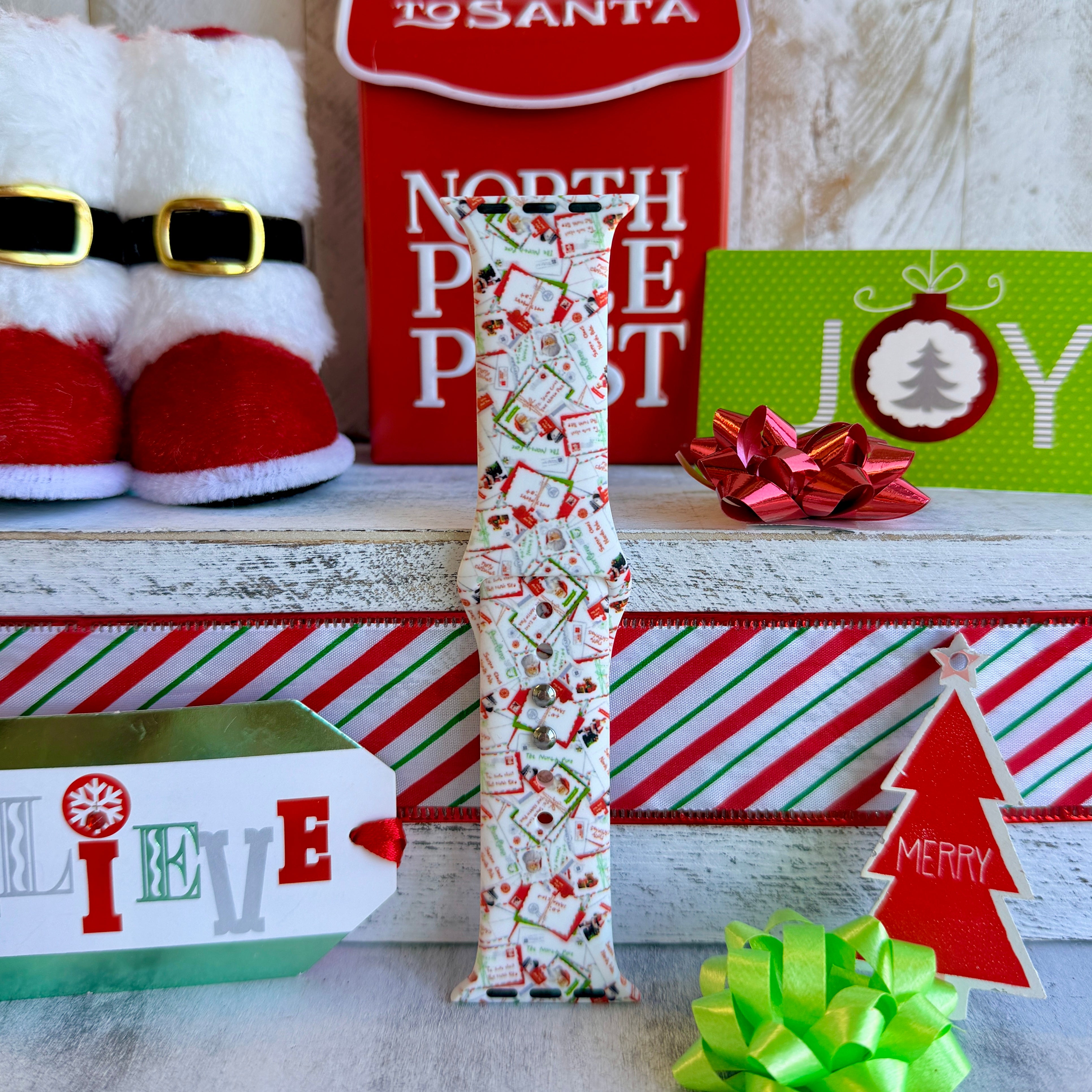 Letters to Santa Apple Watch band styled with Christmas decorations, North Pole box, JOY sign, and holiday wrapping