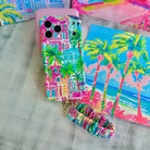 La Palma Villa scrunchie phone wrist strap laid out with the matching tropical resort Wavy Luxe iPhone case