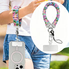 A vibrant Love Riot scrunchie phone wrist strap featuring a colorful neon graffiti "LOVE" and heart design attached to a matching Wavy Luxe phone case on a bright street art background.
