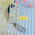 Coastal Catch scrunchie phone wrist strap clipped to the matching Coastal Catch Wavy Luxe iPhone case