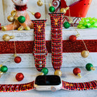 Red and black plaid Apple Watch band with Christmas decorations on a wooden surface.