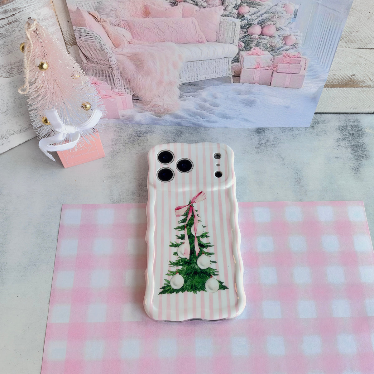 Pretty in PinkMas iPhone case lying on pink gingham paper in a pink and white Christmas setting