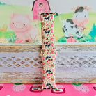 Farm Girl Cutie silicone Apple Watch band with dairy cows, red tractors, chickens, ducks, pink watering cans, strawberries, baskets, and roses on a cream base with pink gingham squares, shown displayed and worn on Apple Watch against a farmhouse country backdrop.
