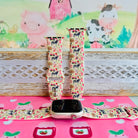Farm Girl Cutie silicone Apple Watch band with dairy cows, red tractors, chickens, ducks, pink watering cans, strawberries, baskets, and roses on a cream base with pink gingham squares, shown displayed and worn on Apple Watch against a farmhouse country backdrop.