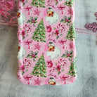 Pink phone case with Christmas-themed design featuring Santa Claus, trees, and presents on a textured surface.