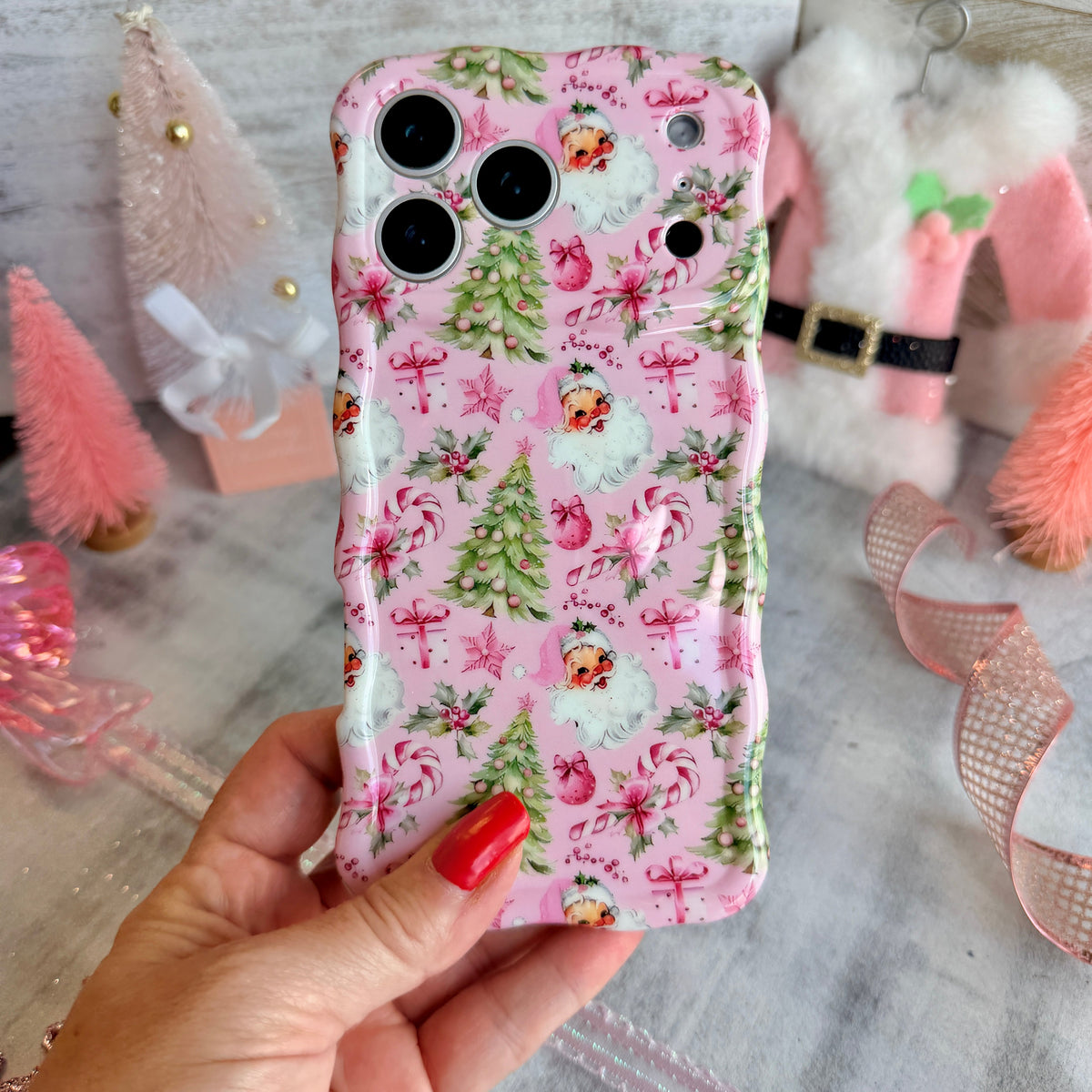 Hand holding the Jolly Pink Santa Wavy Luxe MagSafe iPhone case, vintage Santas and Christmas trees on blush pink