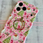 Pink floral phone case with a ring holder on a gray surface