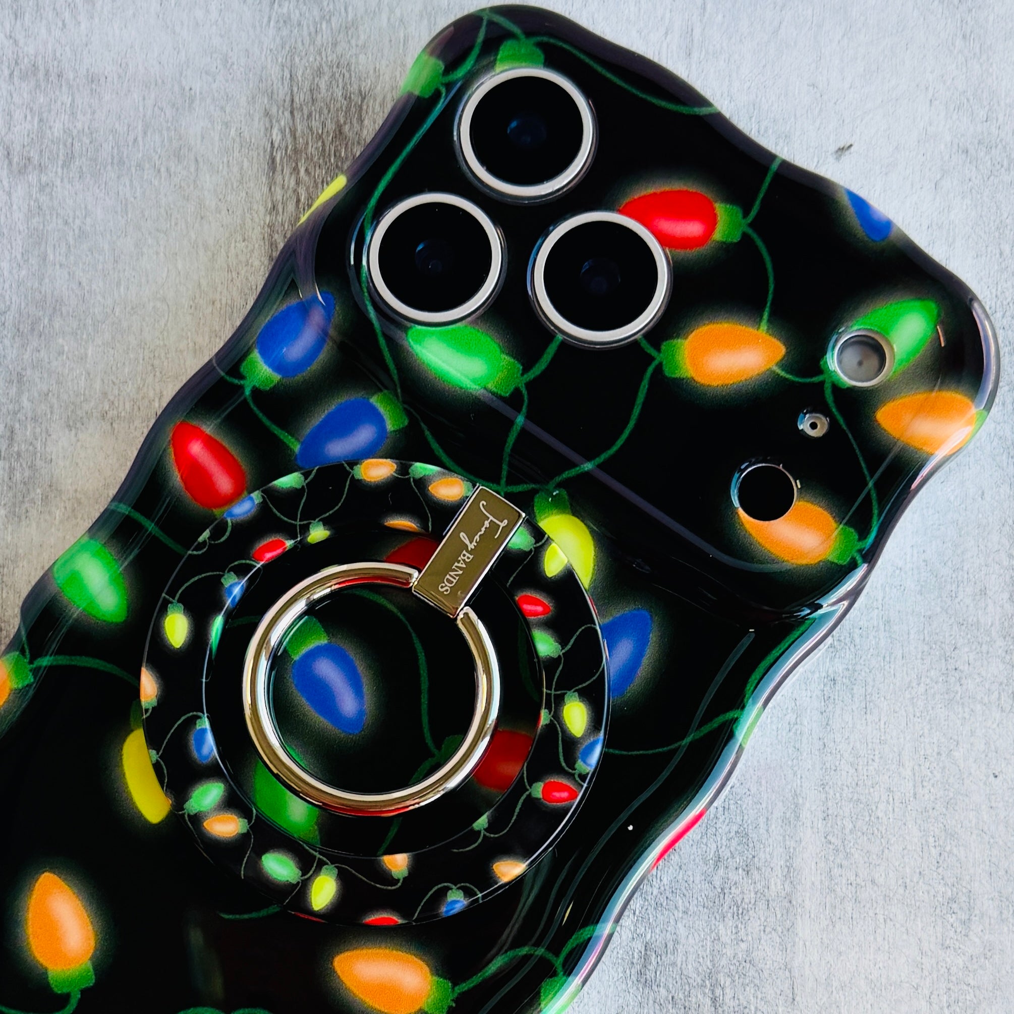 Phone case with colorful Christmas lights design on a gray surface